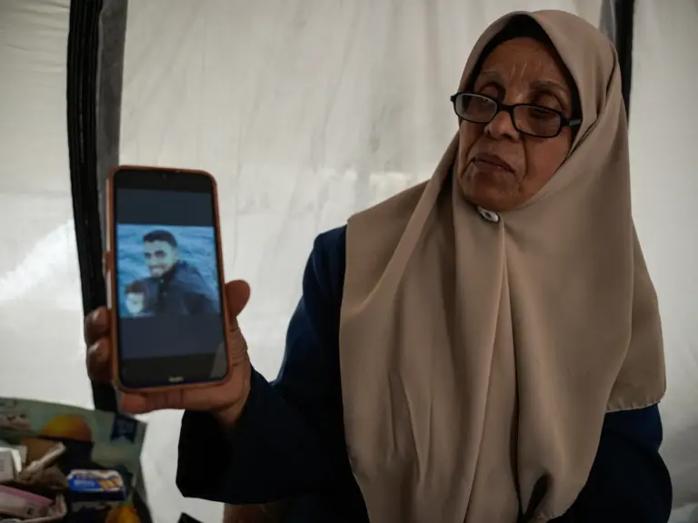 Ina’am Al-Dahdouh holds the photo of her eldest detained son, Mahmoud, at her tent in Tal el hawwa southwest of Gaza city [Omar Ashtawy/ Al Jazeera]