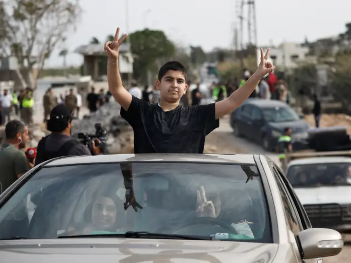 People show victory signs from a vehicle as displaced people make their way back to their homes crossing the bridge linking southern Lebanon to the rest of the country, which was hit earlier in an Israeli strike, after a 10-day ceasefire between Lebanon and Israel went into effect, in Qasmiyeh, Lebanon, April 17, 2026. REUTERS/Louisa Gouliamaki