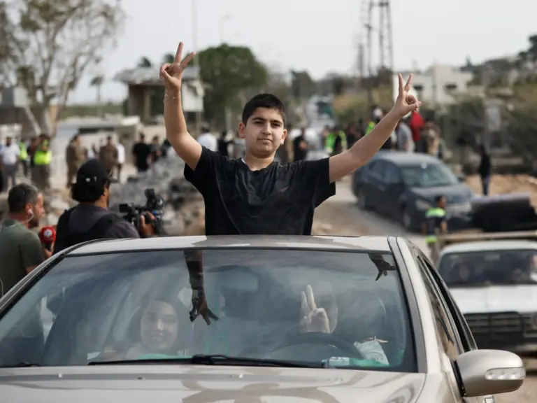People show victory signs from a vehicle as displaced people make their way back to their homes crossing the bridge linking southern Lebanon to the rest of the country, which was hit earlier in an Israeli strike, after a 10-day ceasefire between Lebanon and Israel went into effect, in Qasmiyeh, Lebanon, April 17, 2026. REUTERS/Louisa Gouliamaki