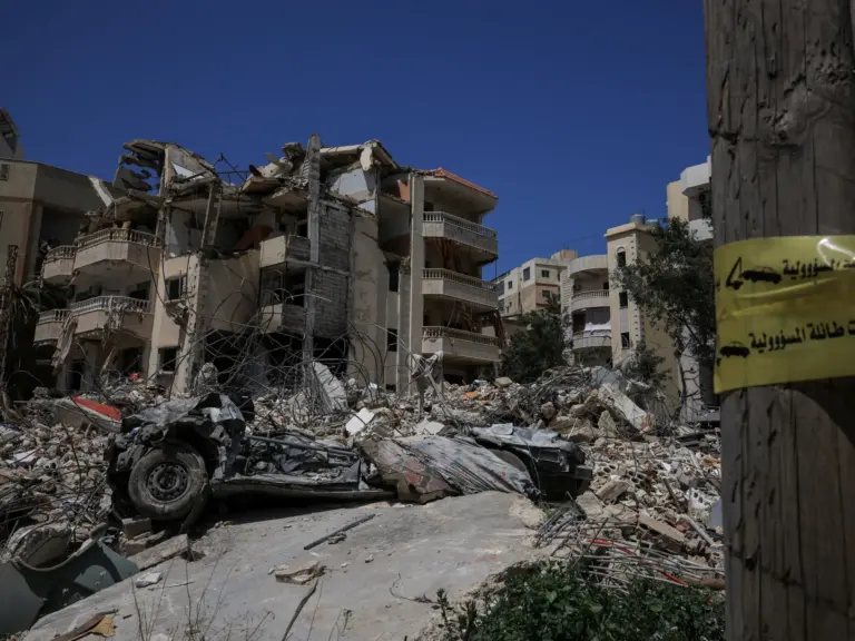 A civil defence ambulance drives by the rubble of buildings