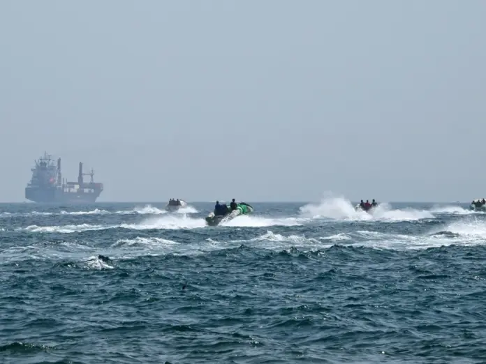 (FILES) Small boats loaded with merchandise sail past the St Kitt's and Nevis-flagged container ship Marsa Victory in the waters of the Strait of Hormuz off the coast of Khasab in Oman’s northern Musandam peninsula on June 25, 2025.