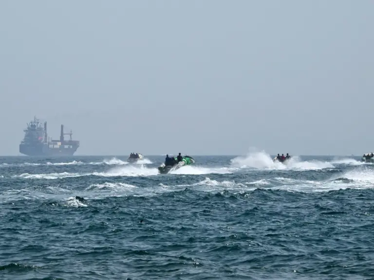 (FILES) Small boats loaded with merchandise sail past the St Kitt's and Nevis-flagged container ship Marsa Victory in the waters of the Strait of Hormuz off the coast of Khasab in Oman’s northern Musandam peninsula on June 25, 2025.