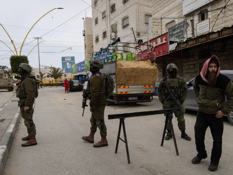 HEBRON, WEST BANK - JANUARY 21: Israeli soldiers stand in front of a military checkpoint set up at one of the entrances to the Jabal Johar area on January 21, 2026 in Hebron. Israeli military initiated a "large-scale" multi-day operation in southern Hebron, targeting the Jabal Johar area to dismantle alleged "terror infrastructure" and seize illegal weapons. The raid involved hundreds of soldiers and heavy machinery leading to a total curfew for approximately 70,000 residents. As the operation c