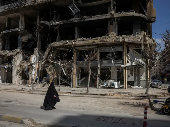 A woman walks past a destroyed building in Beirut