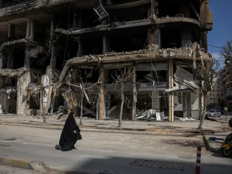 A woman walks past a destroyed building in Beirut