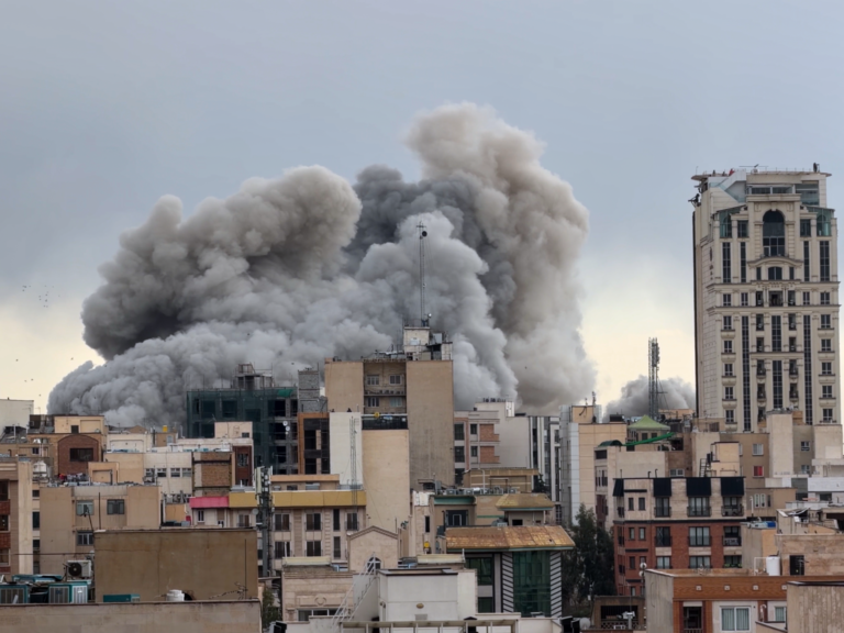 A plume of smoke rises above buildings.