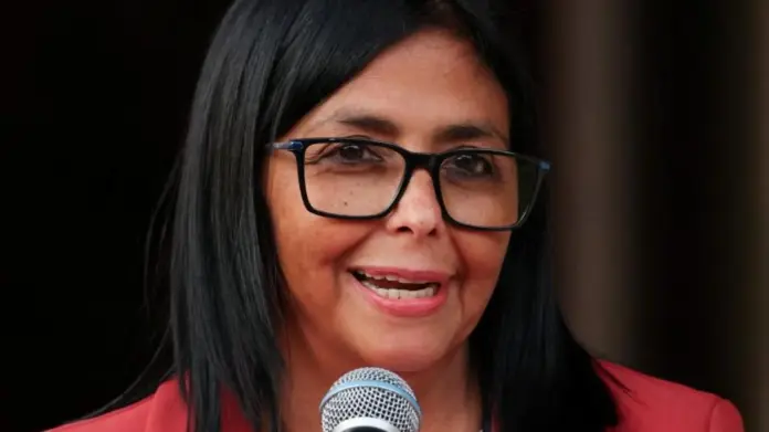 REUTERS/Leonardo Fernandez Viloria Venezuela's interim leader Delcy Rodríguez speaks into a microphone during a meeting with US Interior Secretary Doug Burgum, on 4 March. She is wearing a red jacket and black-rimmed glasses.