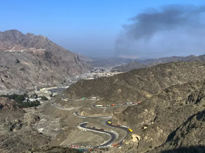 Smoke emits from the Afghan side as trucks are parked along the roadside following cross-border clashes between Pakistan and Afghan forces near the Torkham border crossing point, Pakistan on February 28, 2026.
