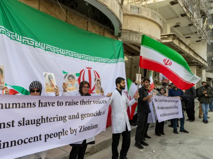 TEHRAN, IRAN - MARCH 7: People hold flags and banners at a protest by medical professionals outside Gandhi Hospital, which was damaged in an airstrike earlier in this week, on March 7, 2026 in Tehran, Iran. The United States and Israel continued their joint attack on Iran that began on February 28. Iran retaliated by firing waves of missiles and drones at Israel, and targeting U.S. allies in the region. (Photo by Majid Saeedi/Getty Images)