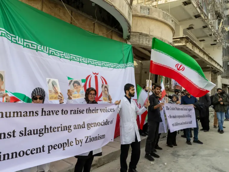 TEHRAN, IRAN - MARCH 7: People hold flags and banners at a protest by medical professionals outside Gandhi Hospital, which was damaged in an airstrike earlier in this week, on March 7, 2026 in Tehran, Iran. The United States and Israel continued their joint attack on Iran that began on February 28. Iran retaliated by firing waves of missiles and drones at Israel, and targeting U.S. allies in the region. (Photo by Majid Saeedi/Getty Images)