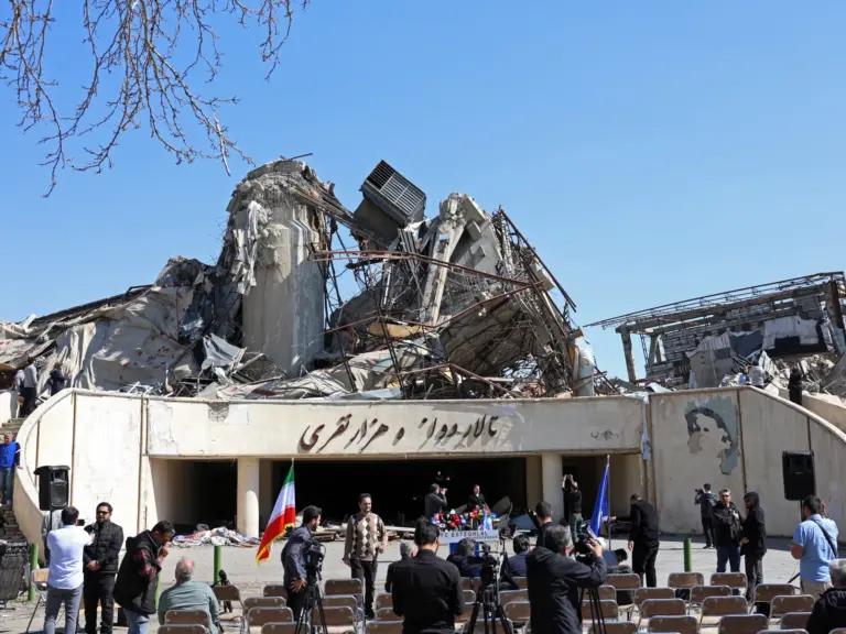 Media representatives gather in front of a heavily damaged building following a strike at the Azadi Sport Complex in Tehran on April 3, 2026.