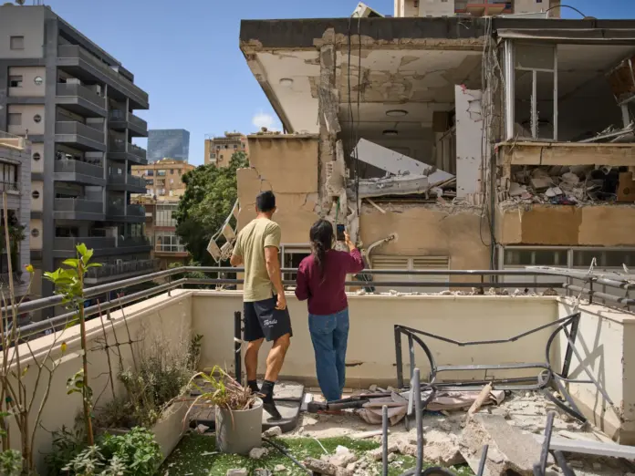 A couple surveys the damage to a neighboring apartment building after it was struck by an Iranian missile in Ramat Gan, Israel, Monday, April 6, 2026. (AP Photo/Oded Balilty)