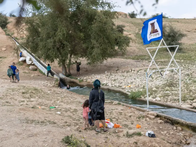 An armed Israeli settler gathers with others at a water slide.