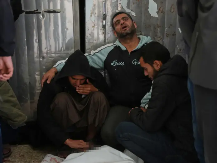 Palestinians mourn over the bodies of men killed in an Israeli strike in al-Bureij refugee camp, before their funeral at Al-Aqsa Hospital in Deir al-Balah