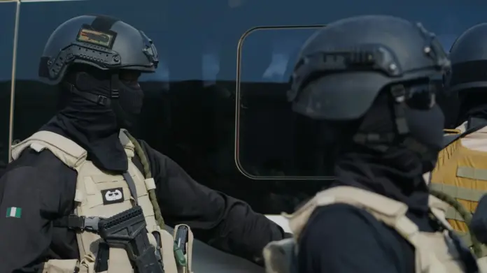 AP Photo/Sunday Alamba Two government forces personnel wearing all black and beige vests.