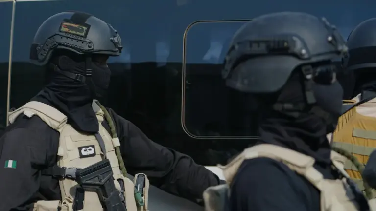 AP Photo/Sunday Alamba Two government forces personnel wearing all black and beige vests.