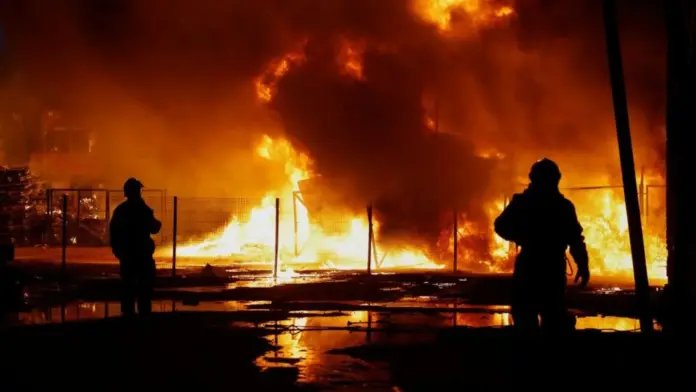 Reuters Two rescuers are silhouetted against a backdrop of fire in Kyiv