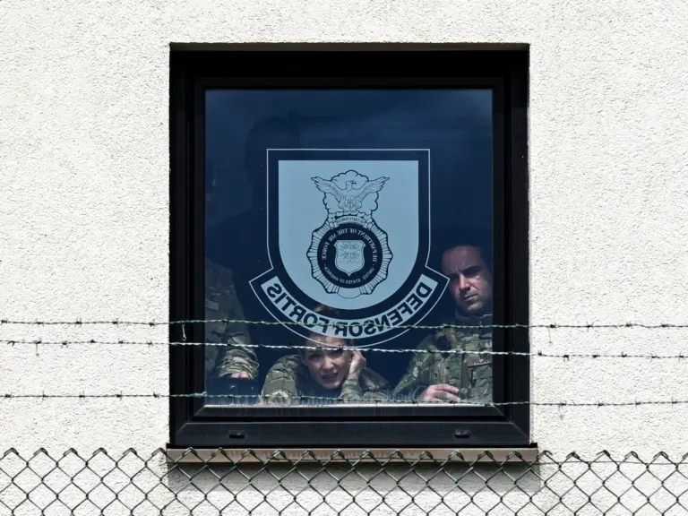 Soldiers stare out of a window at a US military base